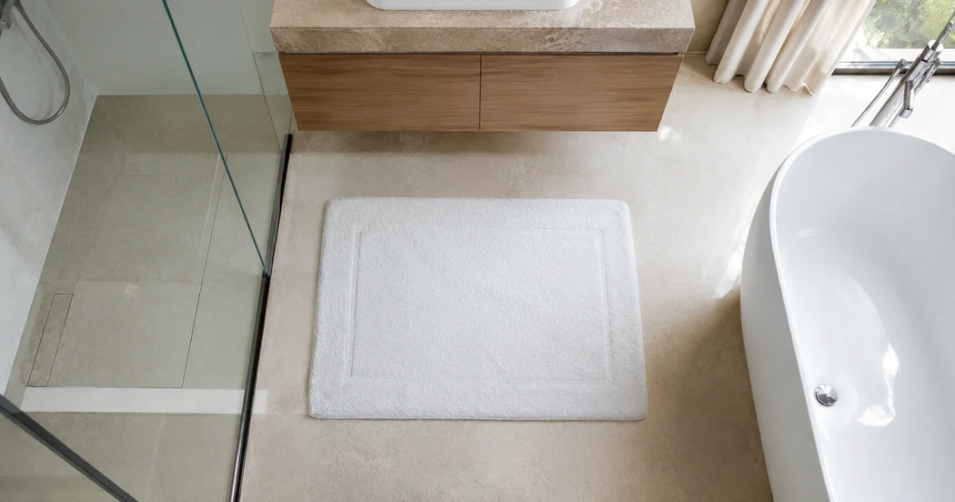 Witte hotelbadmat op een luxe hotelbadkamervloer voor extra veiligheid, comfort en een verzorgde professionele uitstraling.