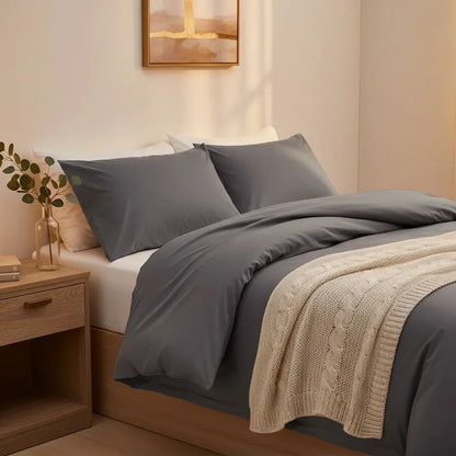 Tweepersoons antraciet dekbedovertrek in warme moderne slaapkamer met houten bedframe en gebreide plaid.