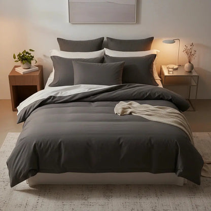 Tweepersoons antraciet dekbedovertrek in moderne slaapkamer met meerdere kussens en warme sfeerverlichting.