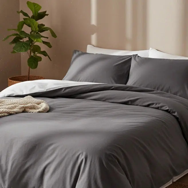 Luxe antraciet dekbedovertrek 240x220 lits-jumeaux van hotelkwaliteit katoen, opgemaakt met witte onderlaag en gebreide beige plaid in een warme, minimalistische slaapkamer met groene kamerplant.