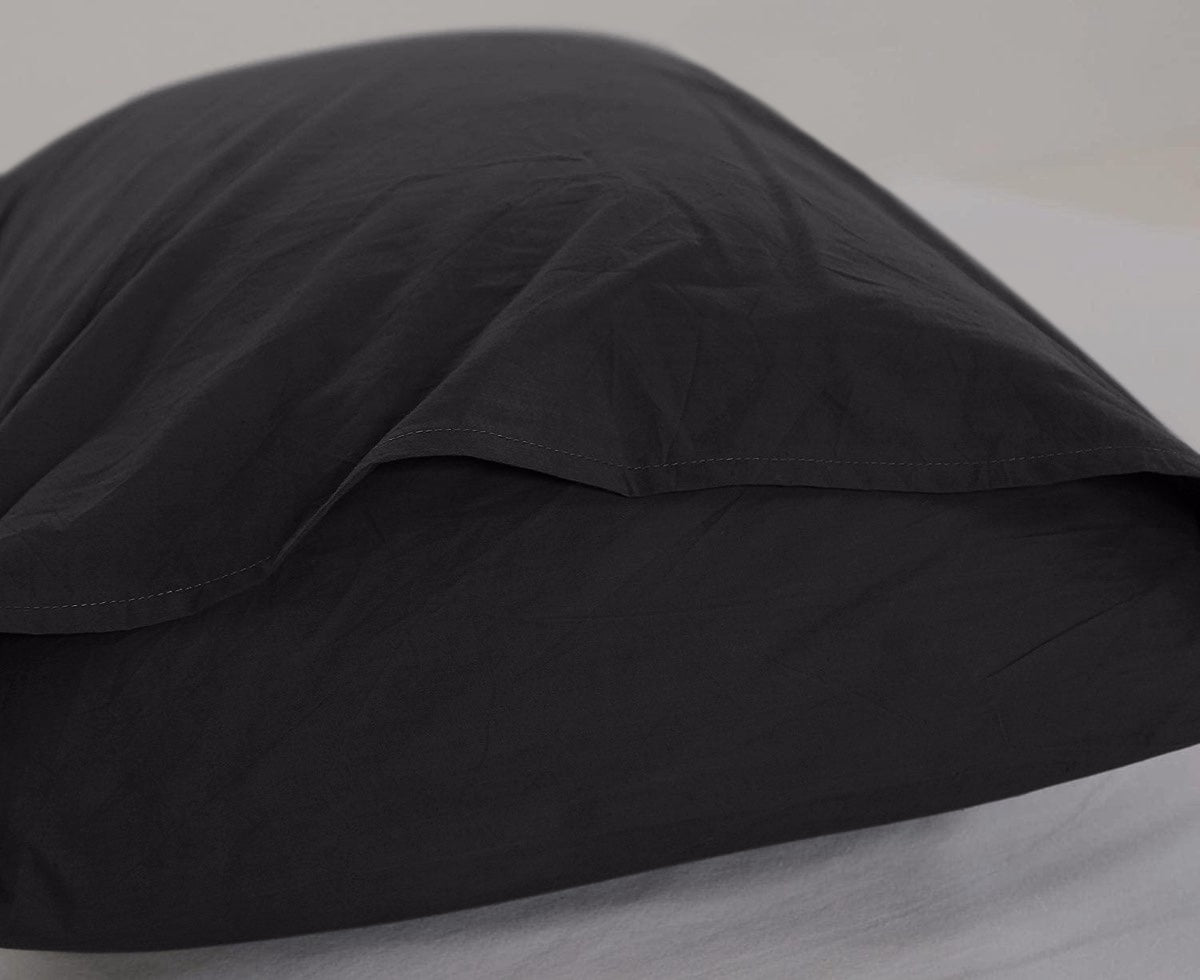 Detail van kussensloop 60x70 bij zwart katoenen dekbedovertrek 200x200 - effen ontwerp en flapsluiting uni - Beterkatoen