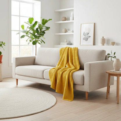 een gele plaid op een bank. de plaid is van 100% katoen