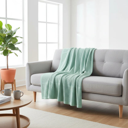 katoenen plaid van beterkatoen op een grijze bank. de plaid is mint groen