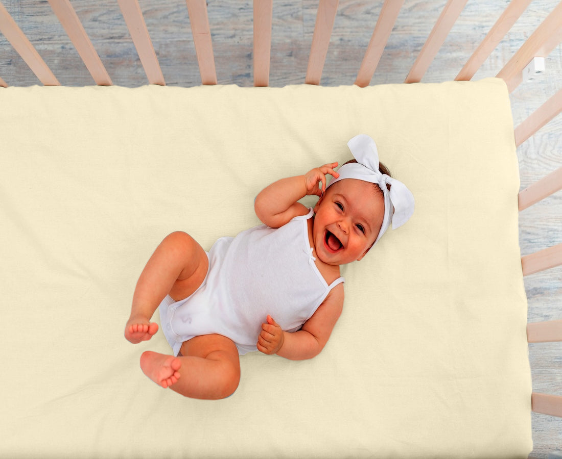 Baby slaapt op jersey kinderhoeslaken creme – zacht, ademend en huidvriendelijk katoen – Beterkatoen